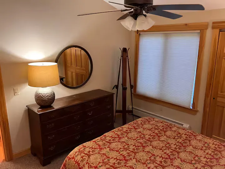 Bedroom with a bed, dresser, lamp, mirror, and ceiling fan.