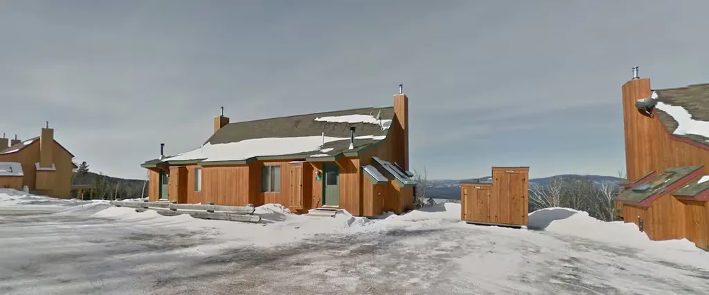 Wooden cabins with snow on roofs in a snowy landscape.